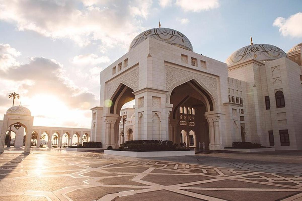 a large building with a mosque with the sun behind it
