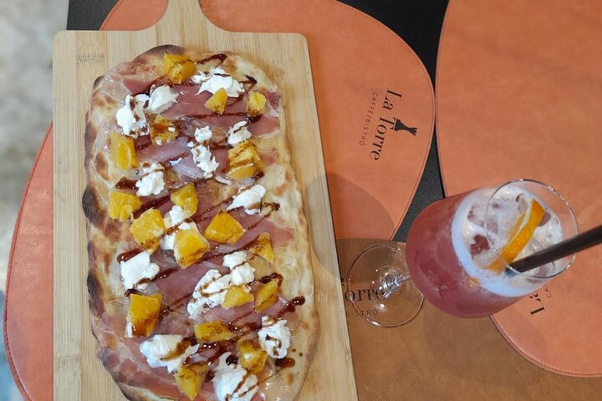 egy pizza egy vágódeszkán egy ital mellett