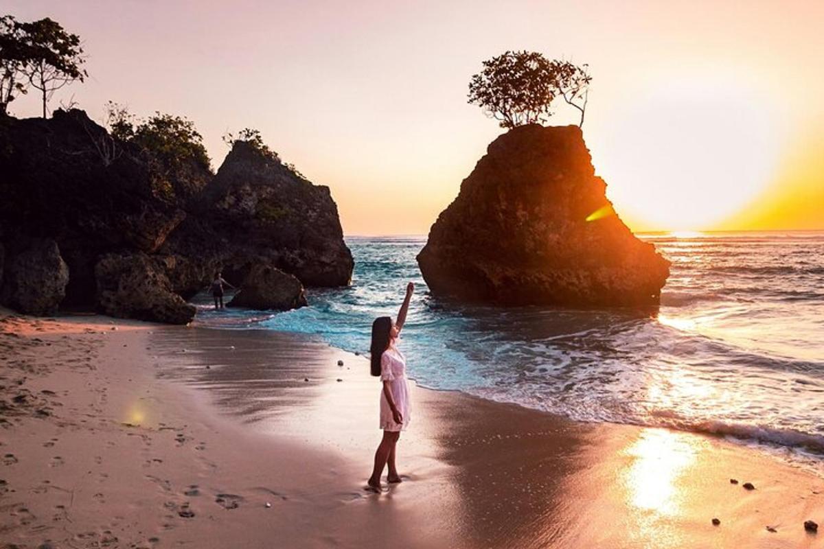 una persona parada en una playa con un árbol sobre una roca