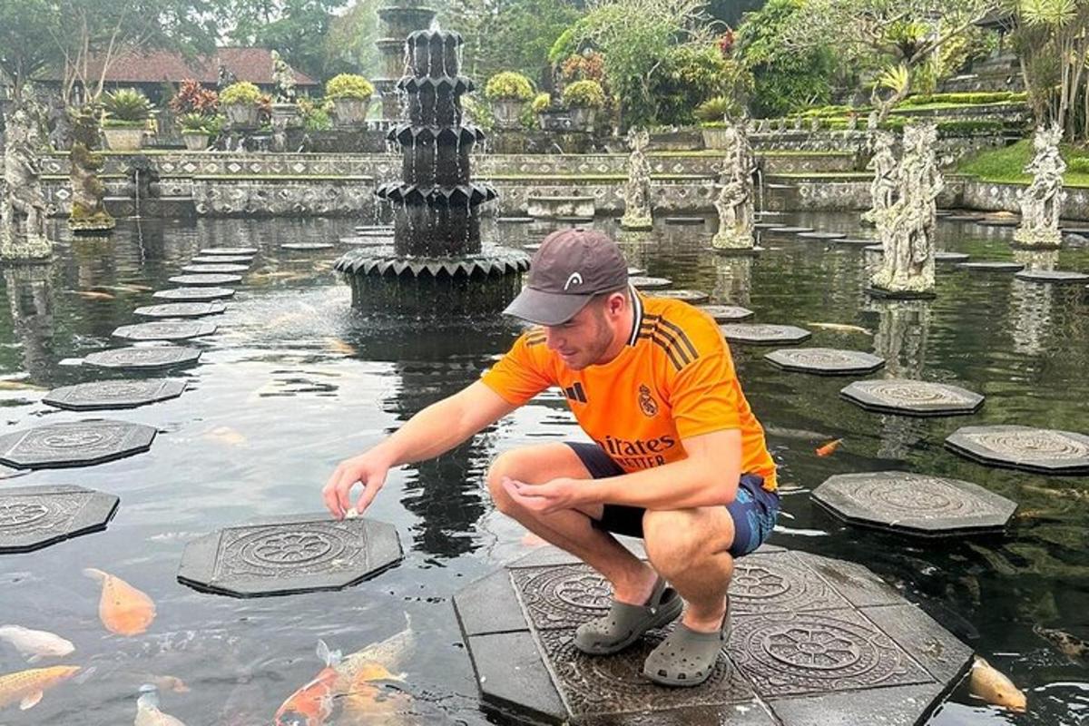 Mees kükitab tiigis ja toidab kalu