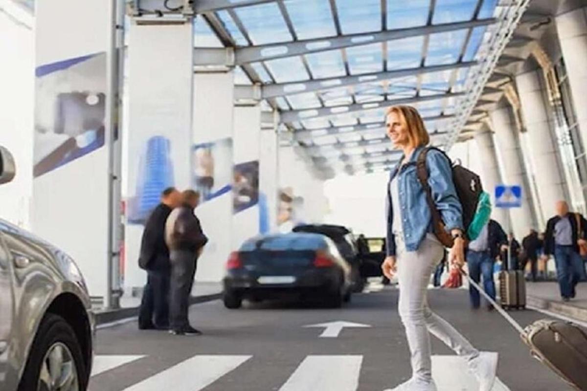 a woman walking across a street with a suitcase