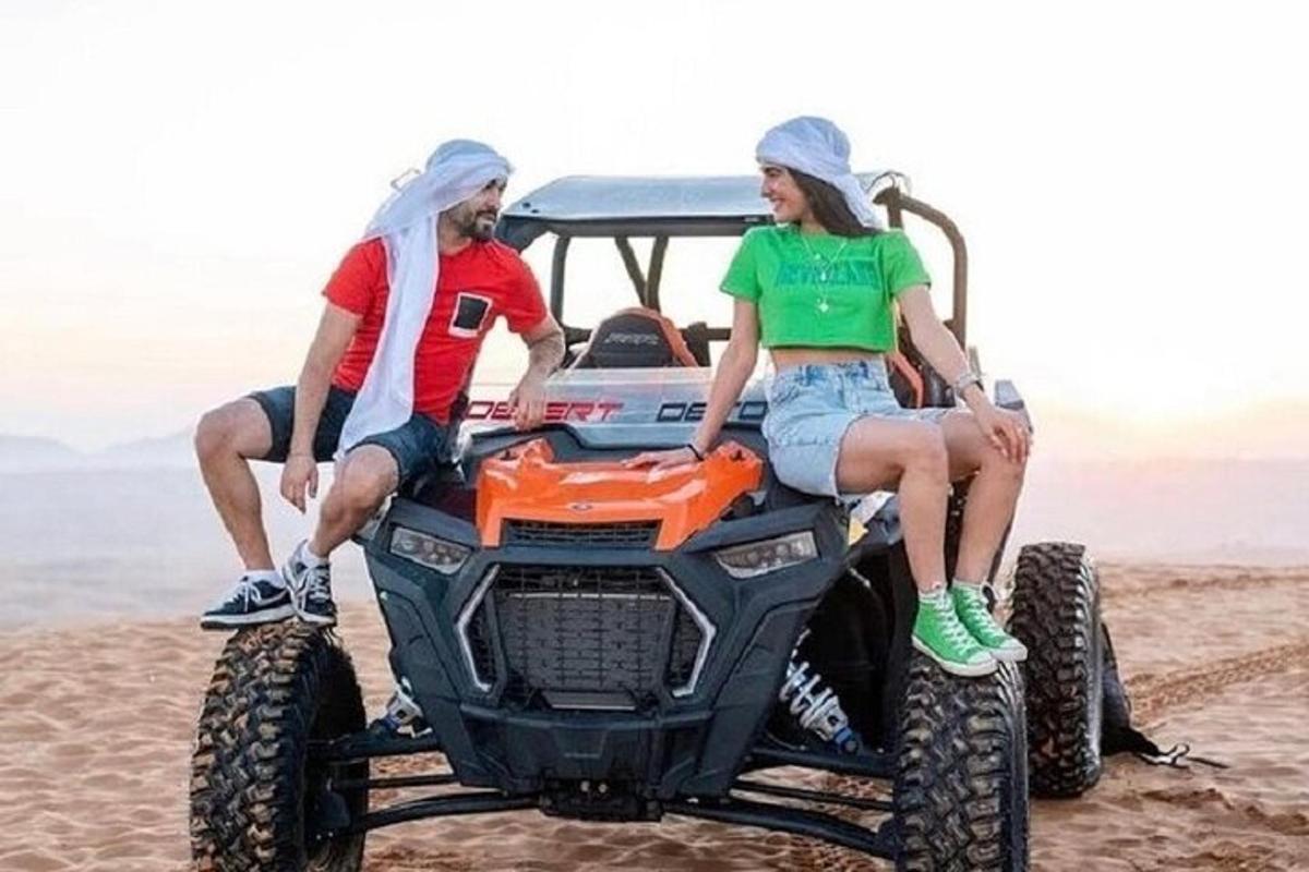 dva lidé sedící na čtyřkolce na pláži