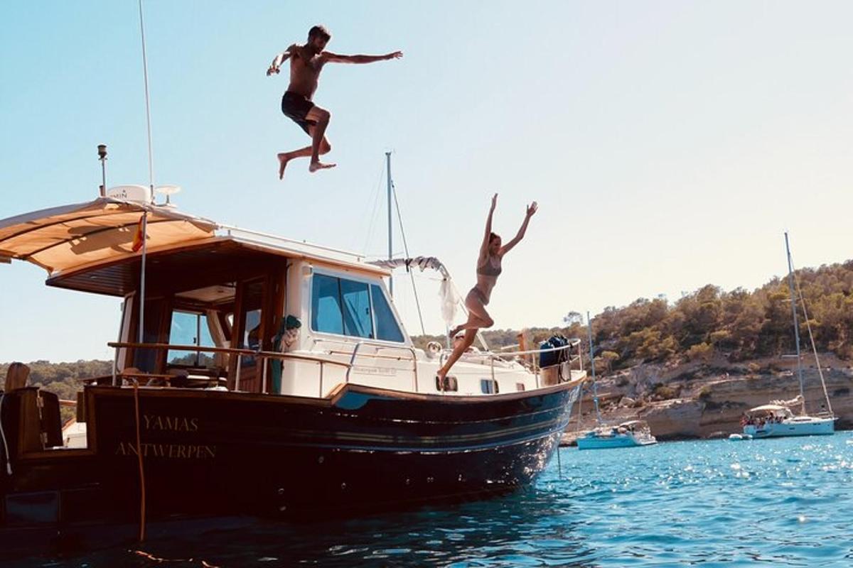 two people jumping off of a boat in the water