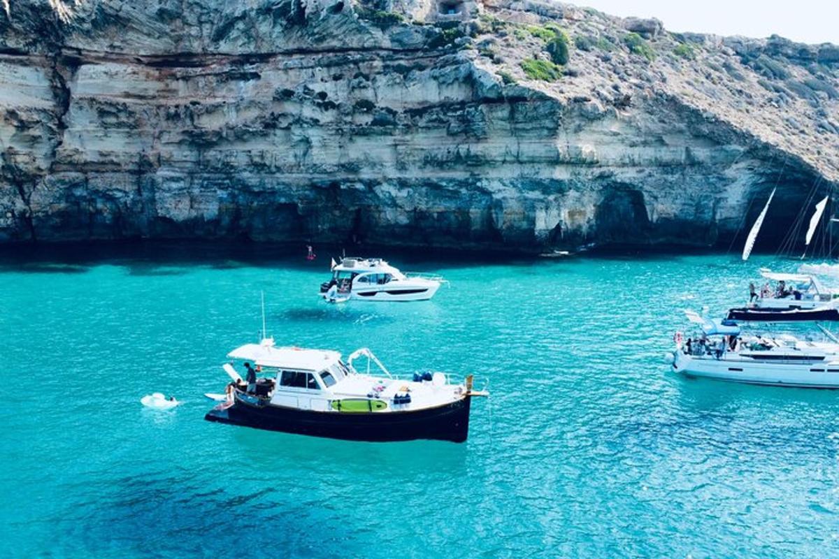 three boats floating in the water near a cave