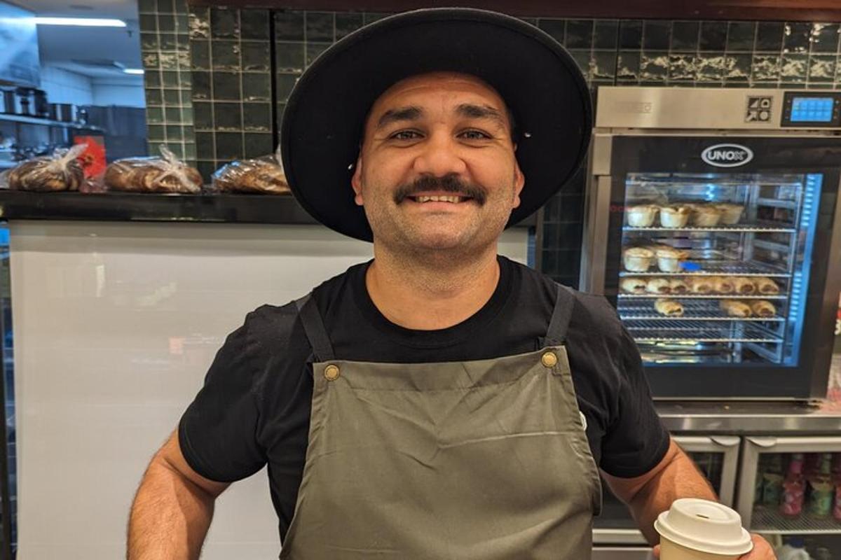 un uomo che indossa un cappello in piedi in una panetteria