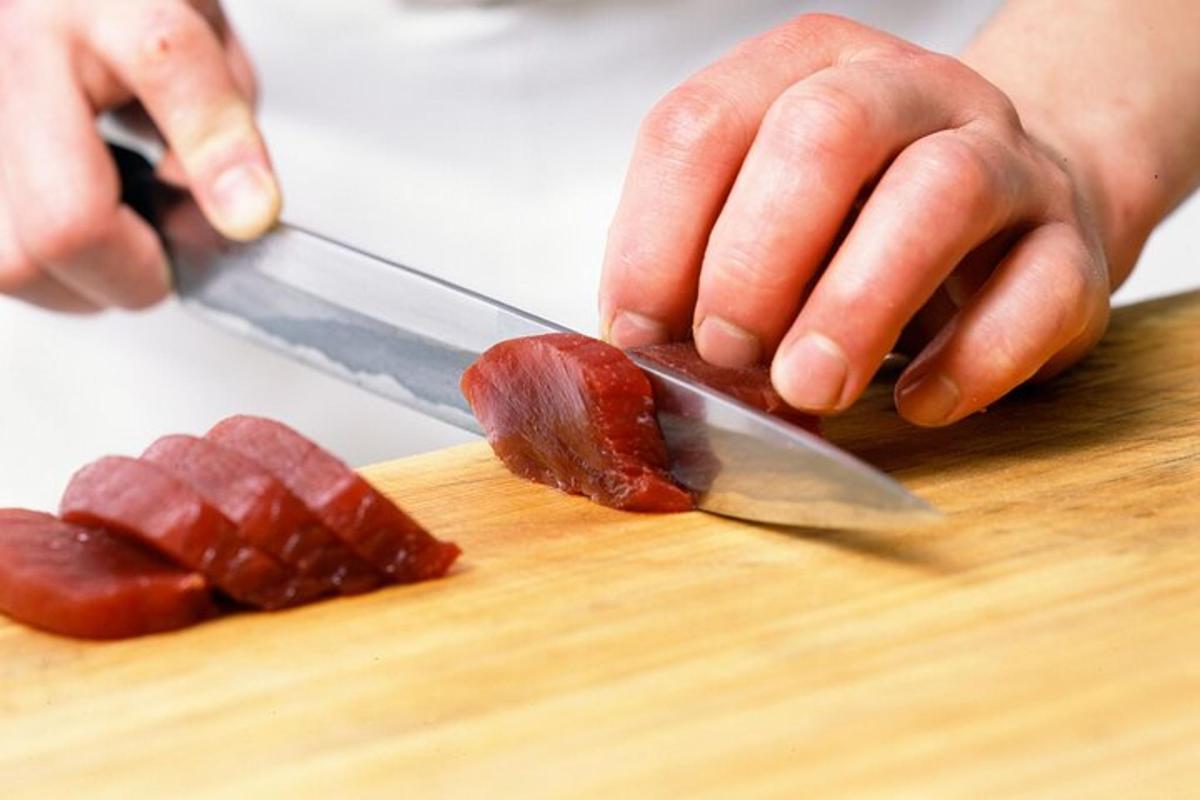 osoba krájející kus slaniny na prkénku
