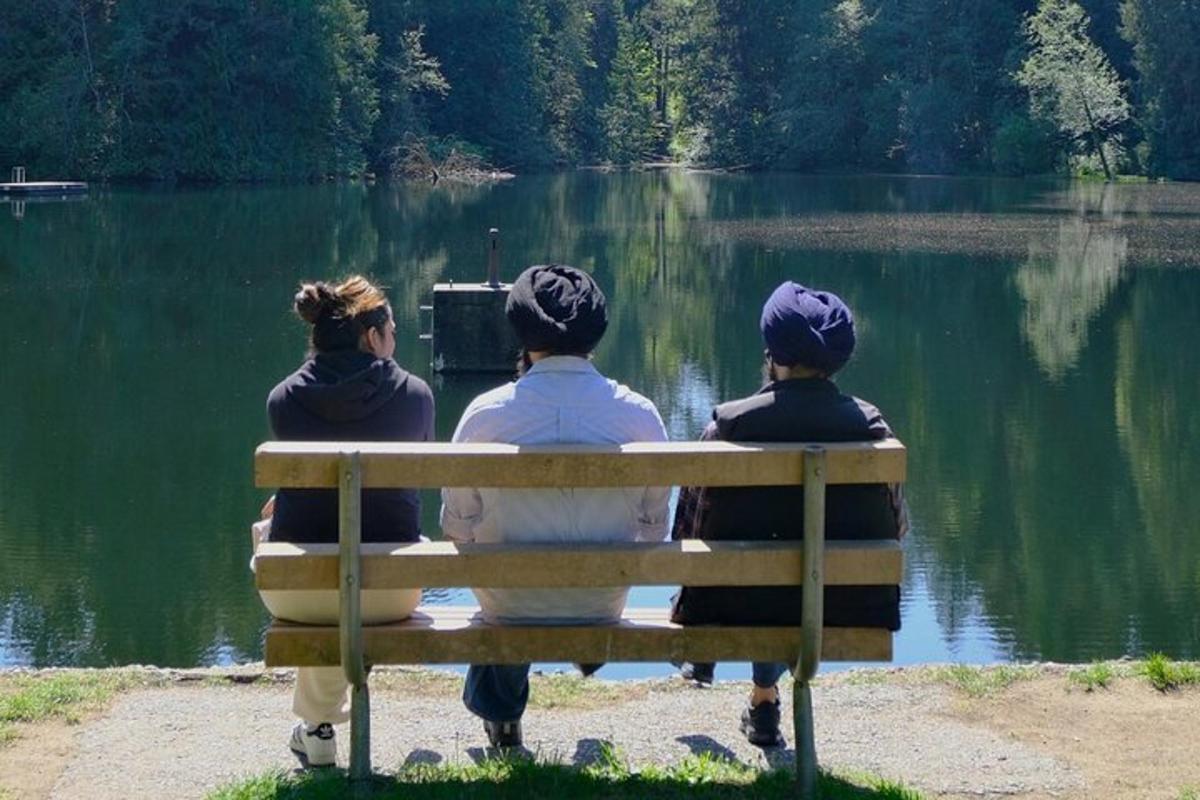 kolm inimest istuvad pingil ja vaatavad järve