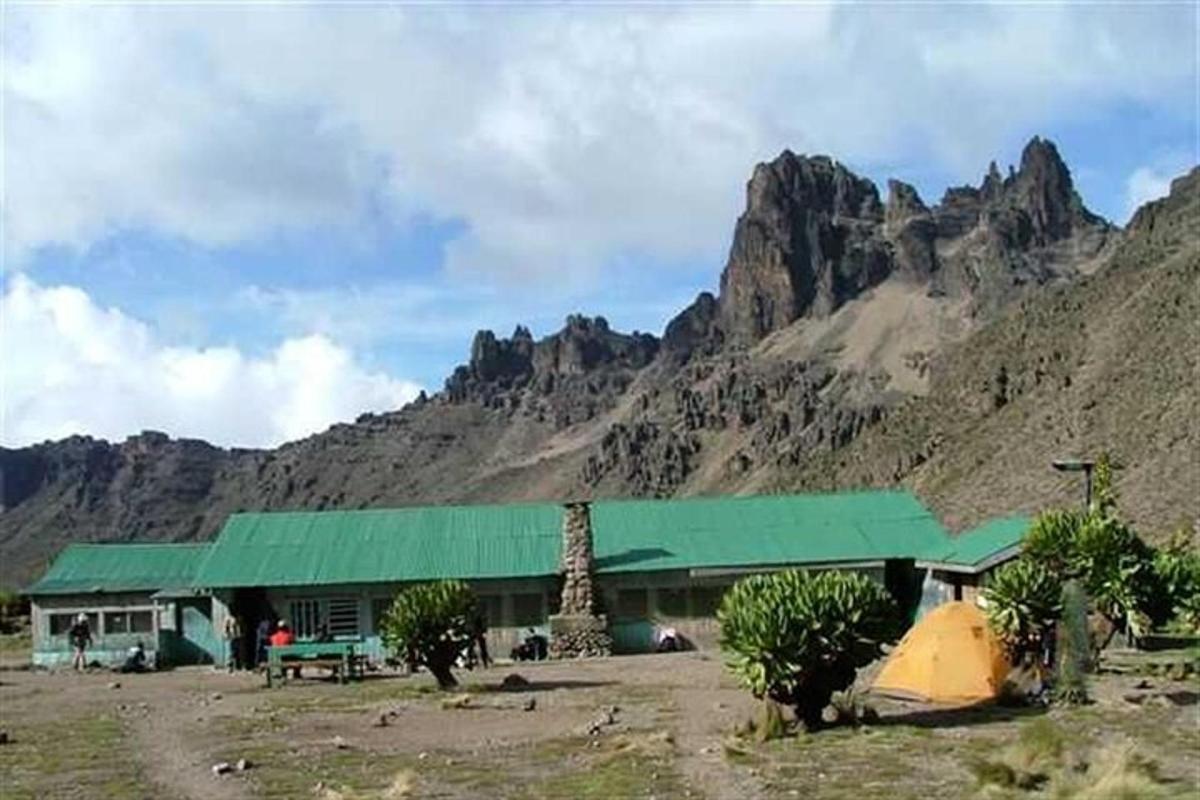 a building with a green roof in front of a mountain