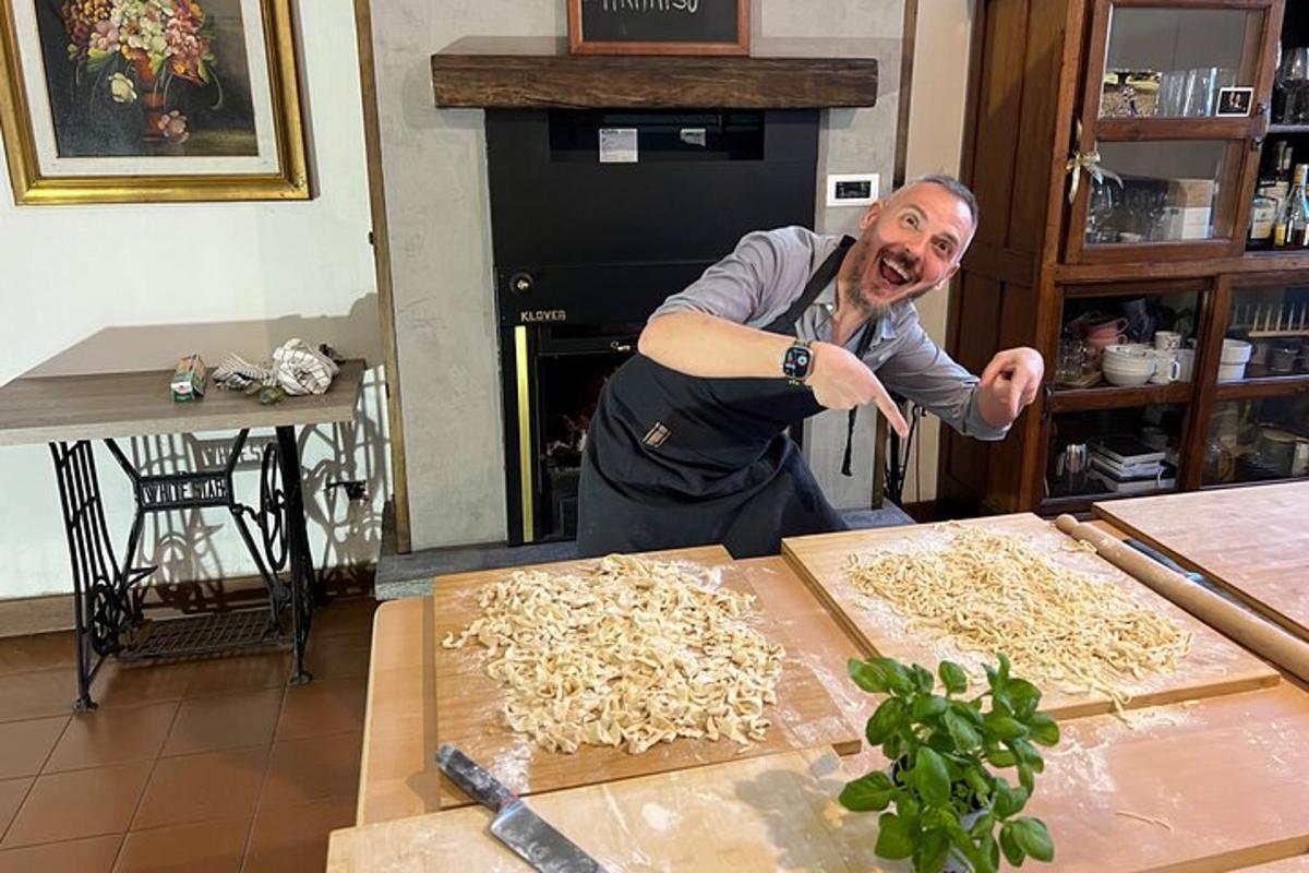 Un hombre de pie en una cocina preparando fideos.