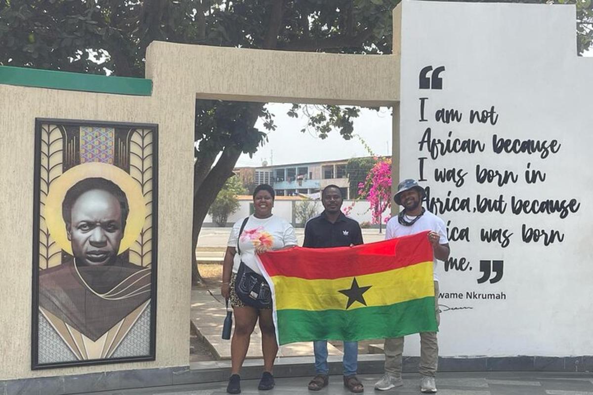 Un grupo de personas de pie frente a un cartel con una bandera.