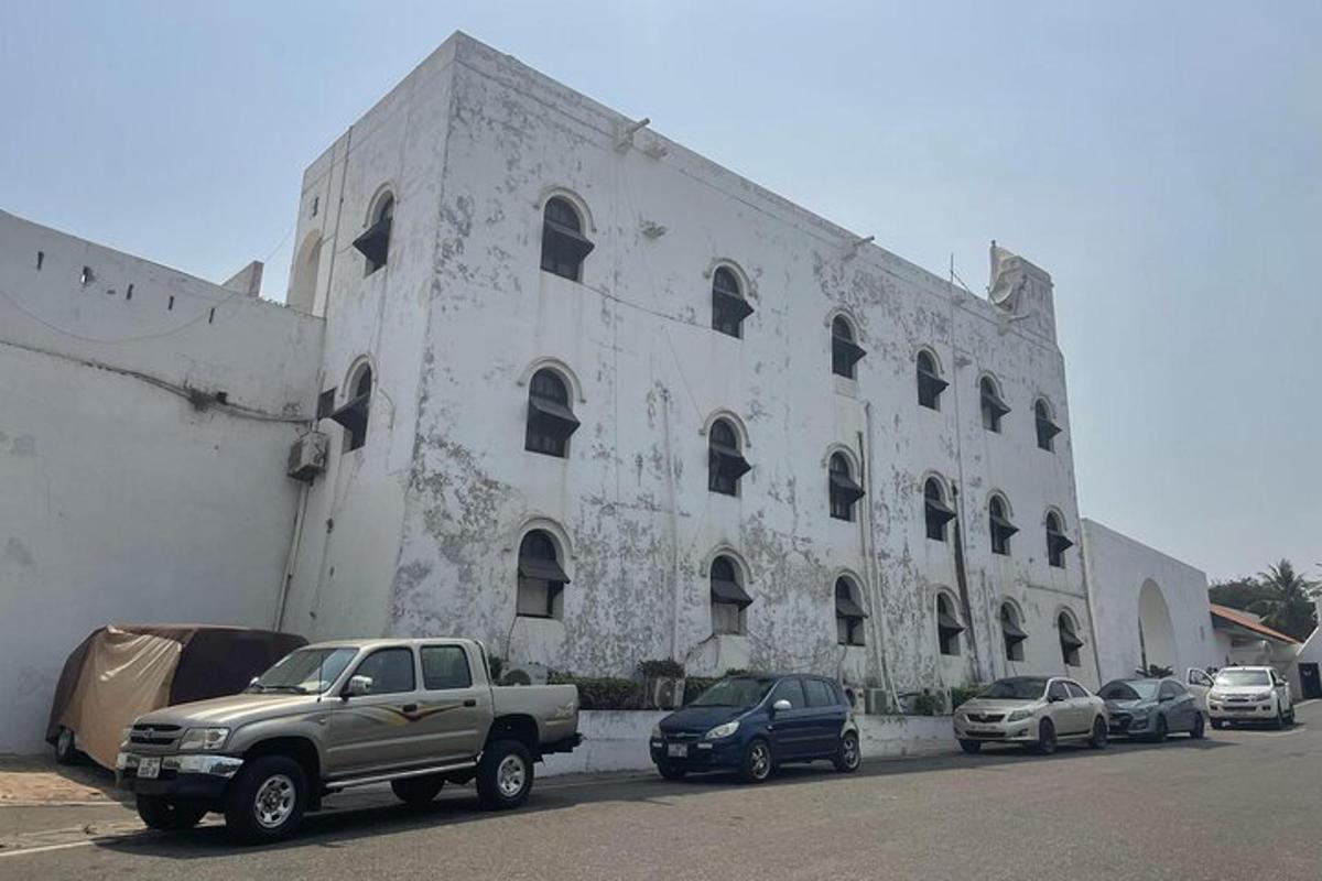 Un gran edificio blanco con coches aparcados delante.