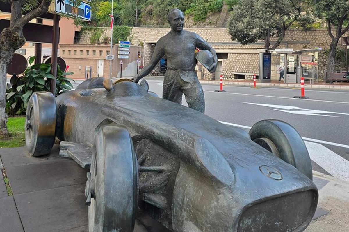 Una estatua de un hombre de pie junto a un coche de carreras.