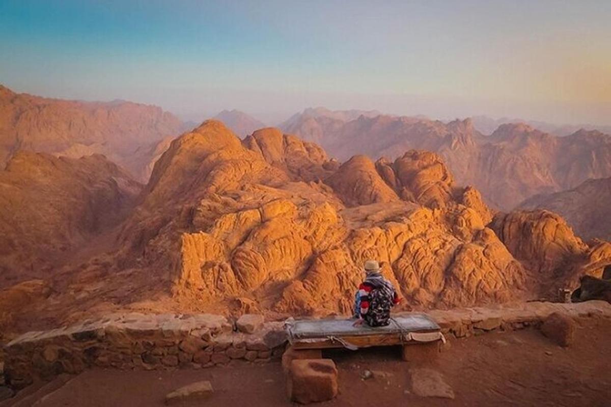 a person sitting on a bench looking out over a mountain