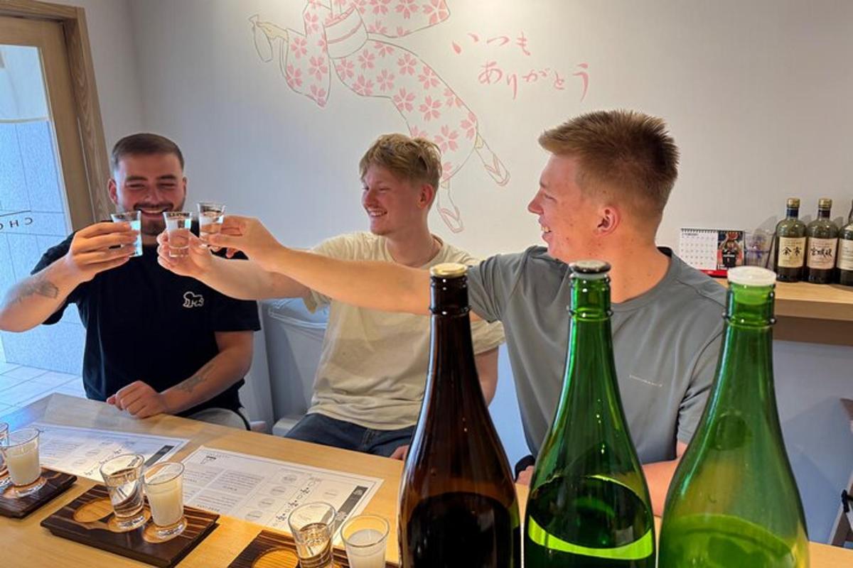 un grup de oameni așezați la o masă cu sticle de vin