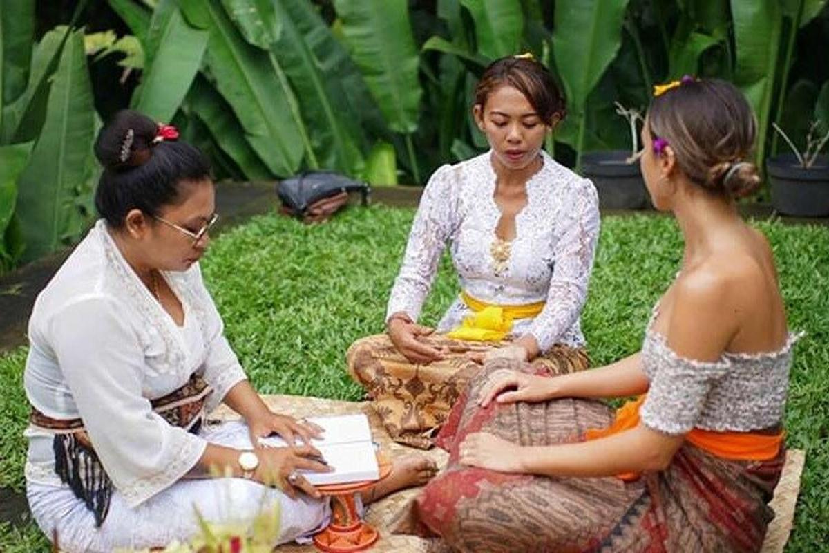 sekelompok tiga wanita duduk di atas rumput