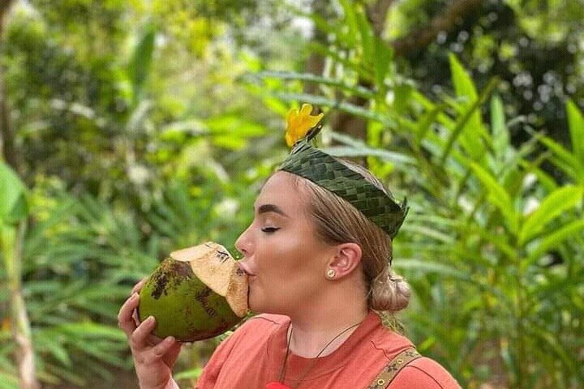 žena jí kokosový ořech s květinou na hlavě