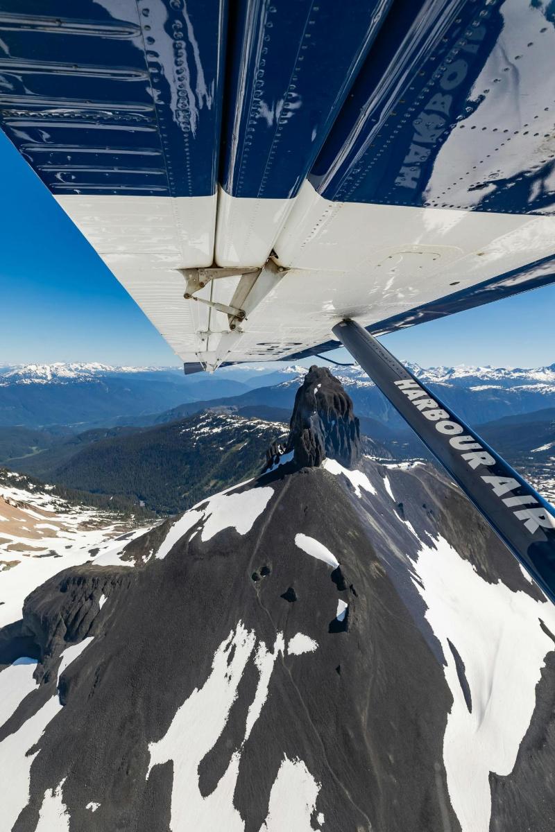una vista dall'ala di un aereo che vola sopra una montagna innevata