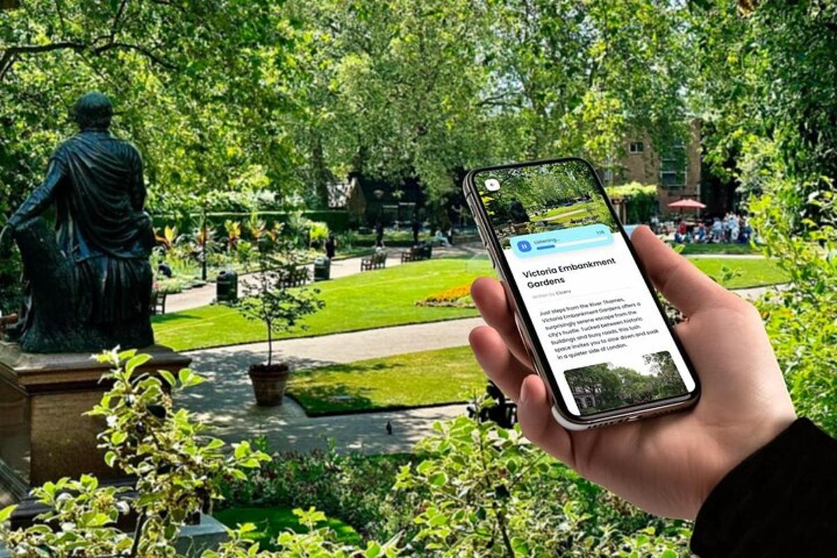 una persona sosteniendo un teléfono celular frente a una estatua