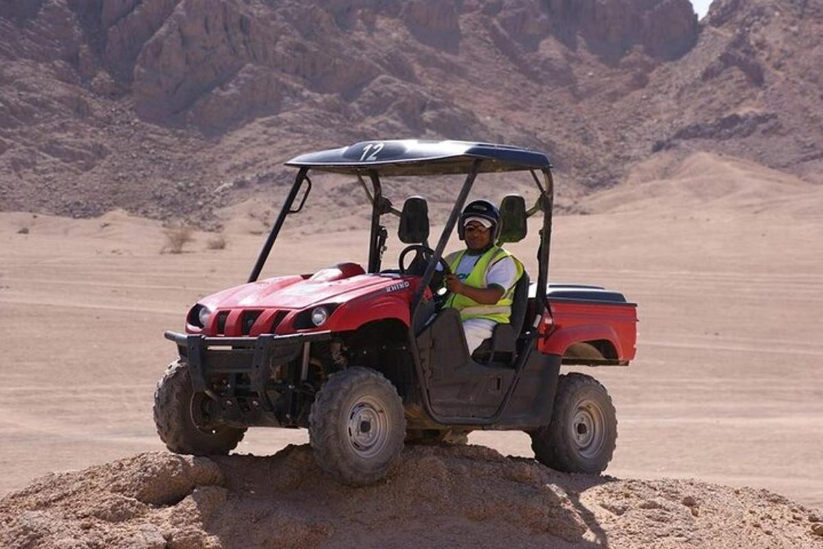 un bărbat care conduce un ATV roșu în deșert
