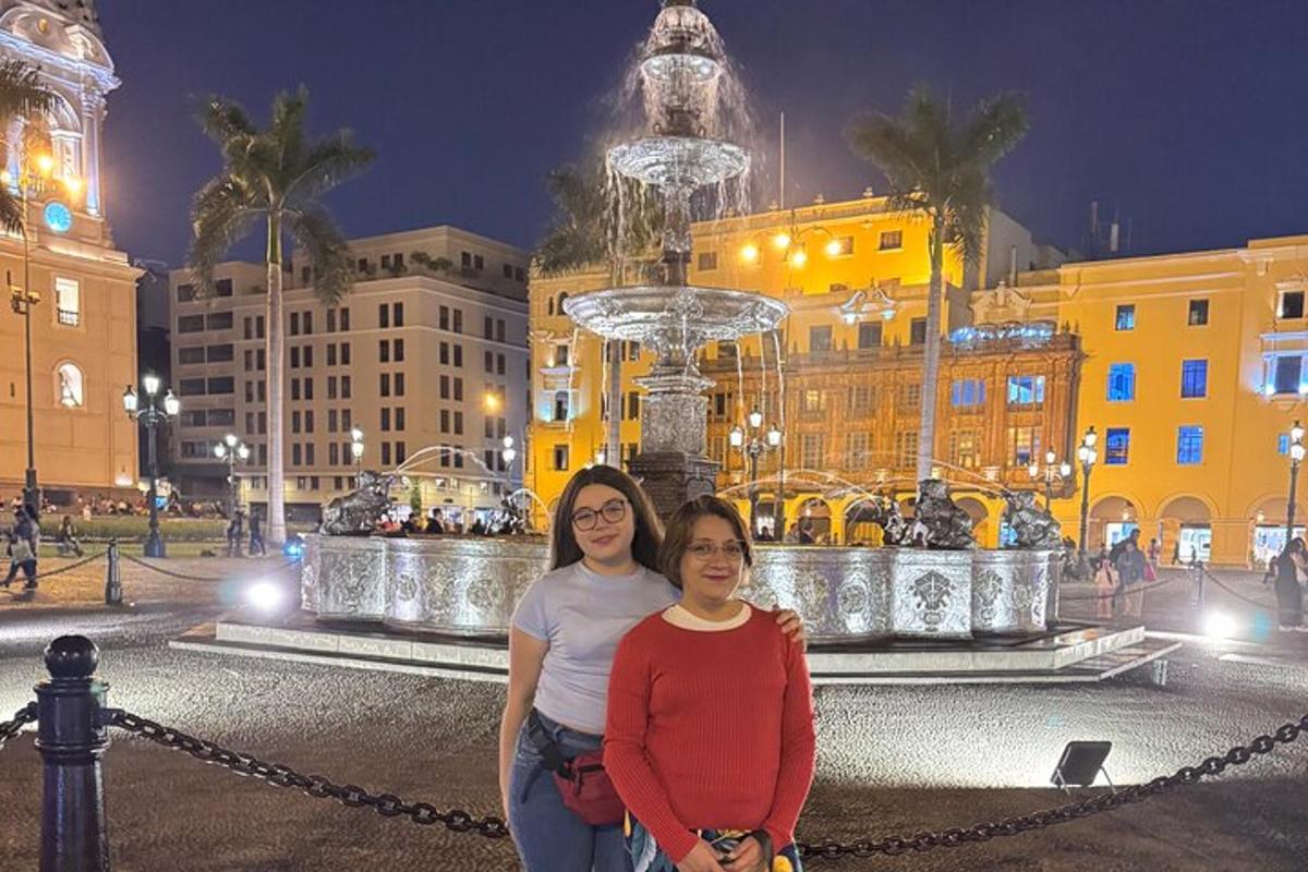 zwei Frauen stehen nachts vor einem Brunnen