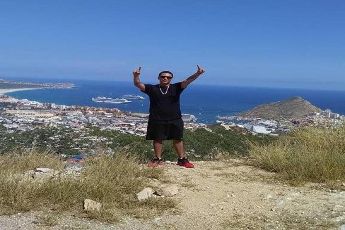 Un hombre parado en la cima de una colina con las manos en alto.