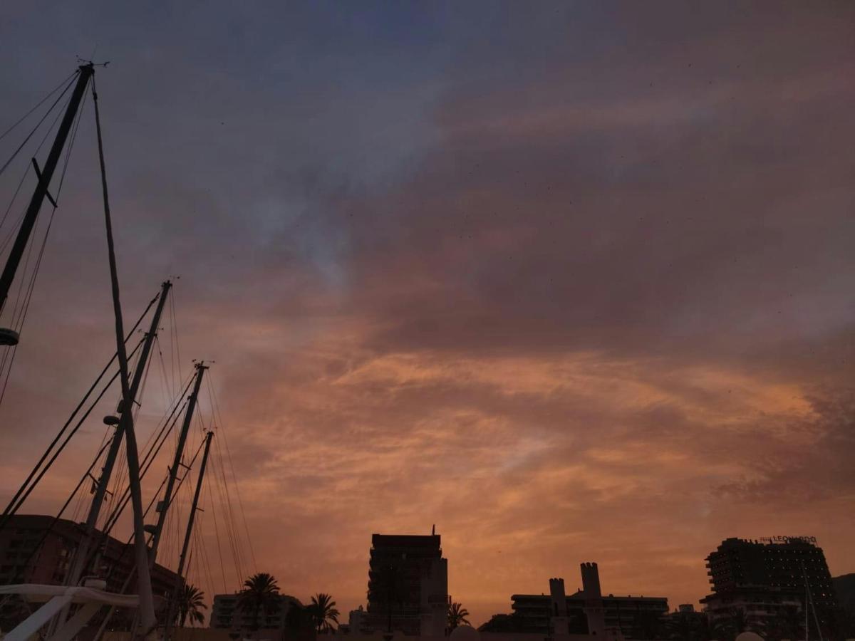 un cel ennuvolat a la posta de sol amb vaixells en una ciutat