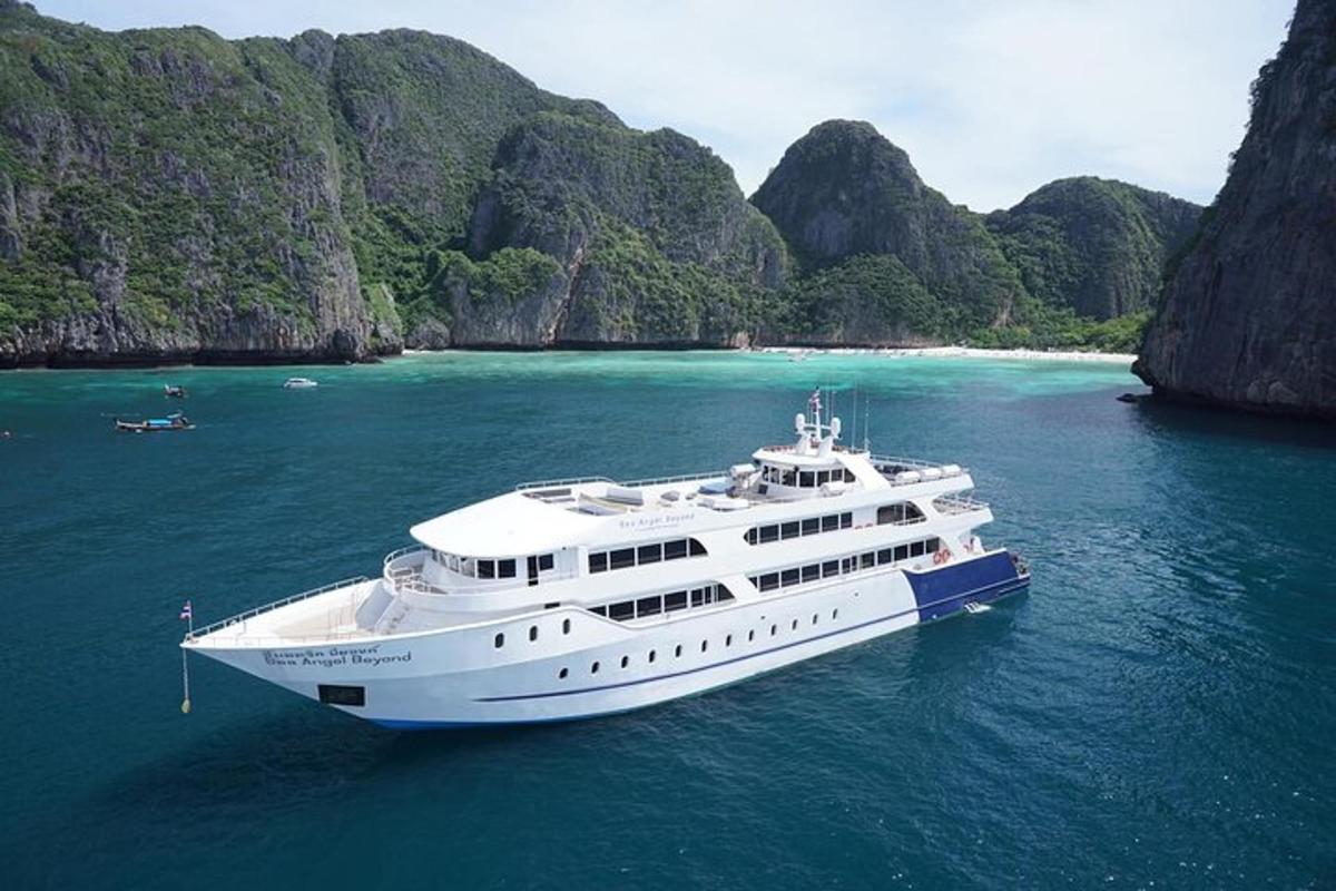 a large white yacht in the water near some cliffs
