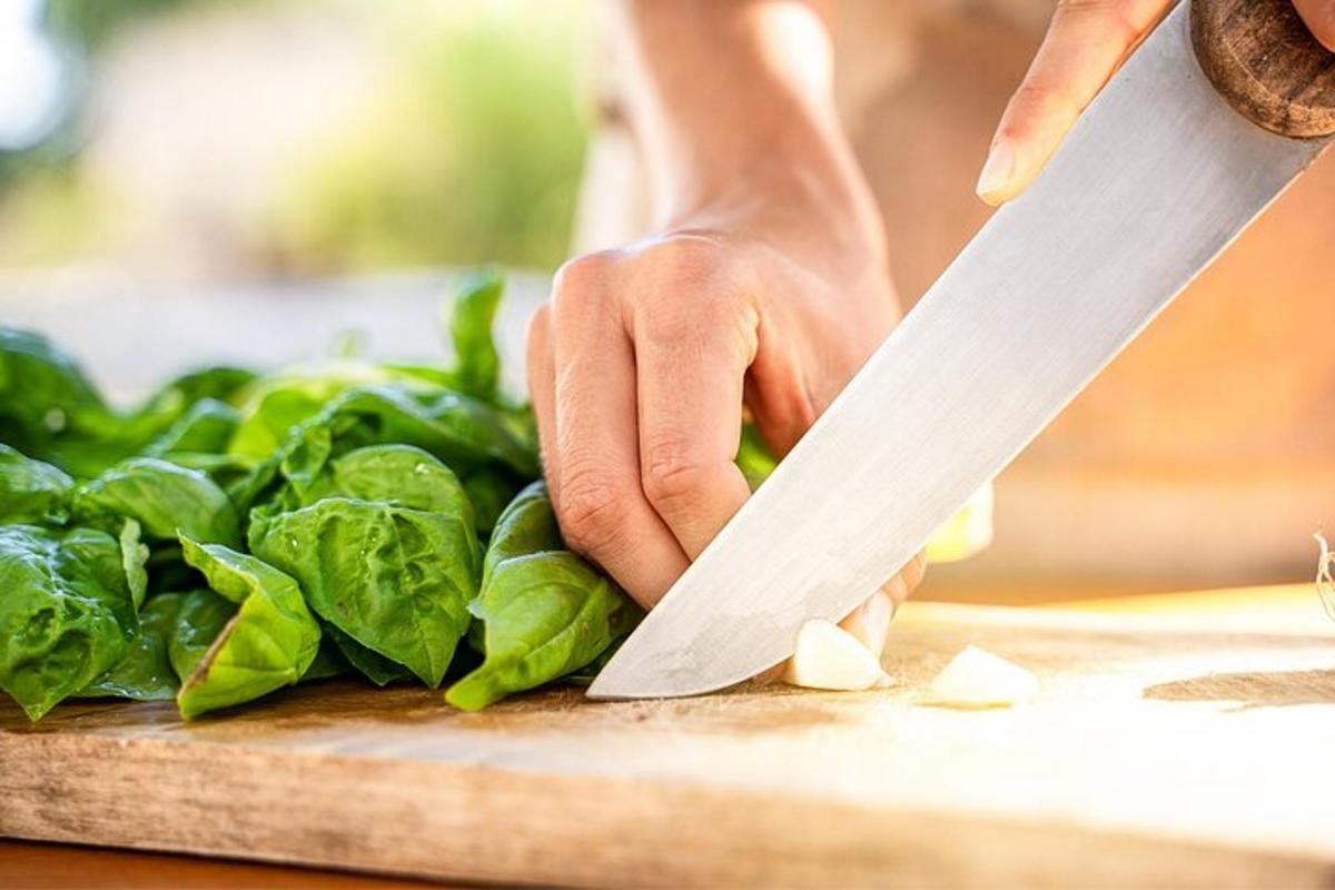 osoba krájející špenát na prkénku nožem