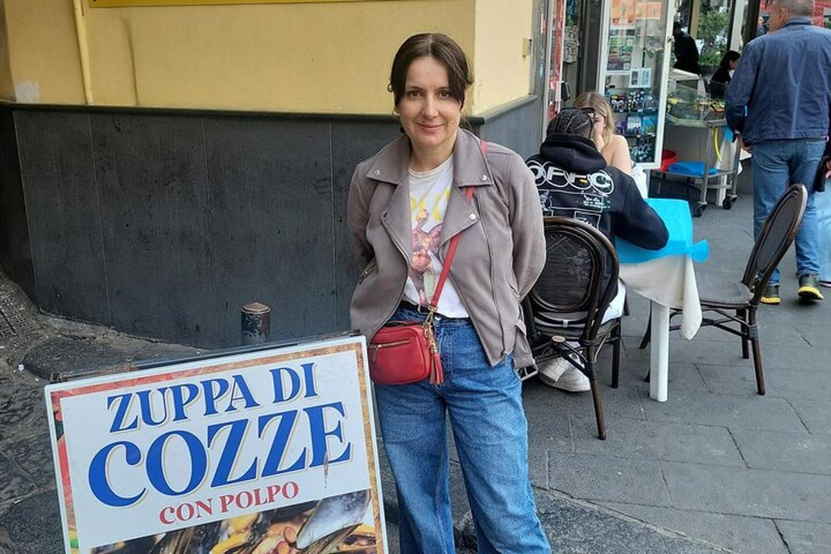 una donna in piedi accanto a un cartello su un marciapiede