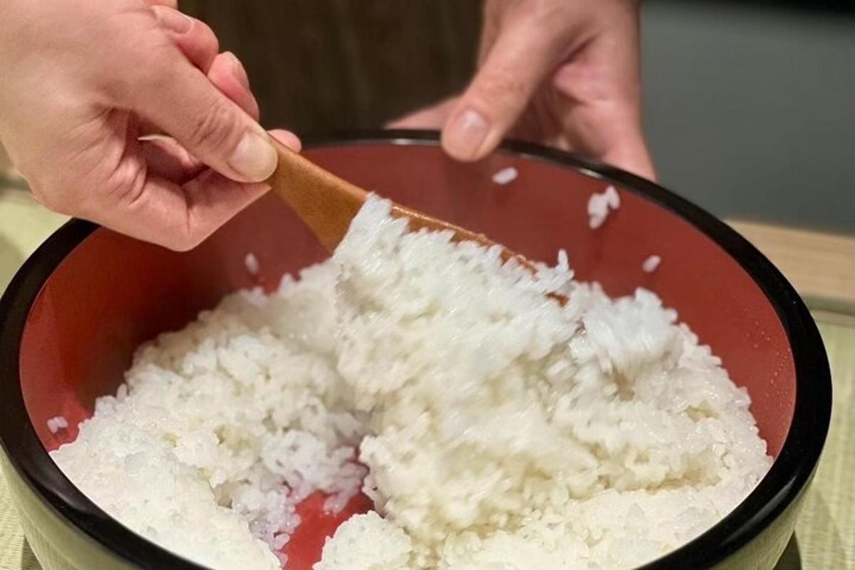 a person holding a wooden spoon in a bowl of rice