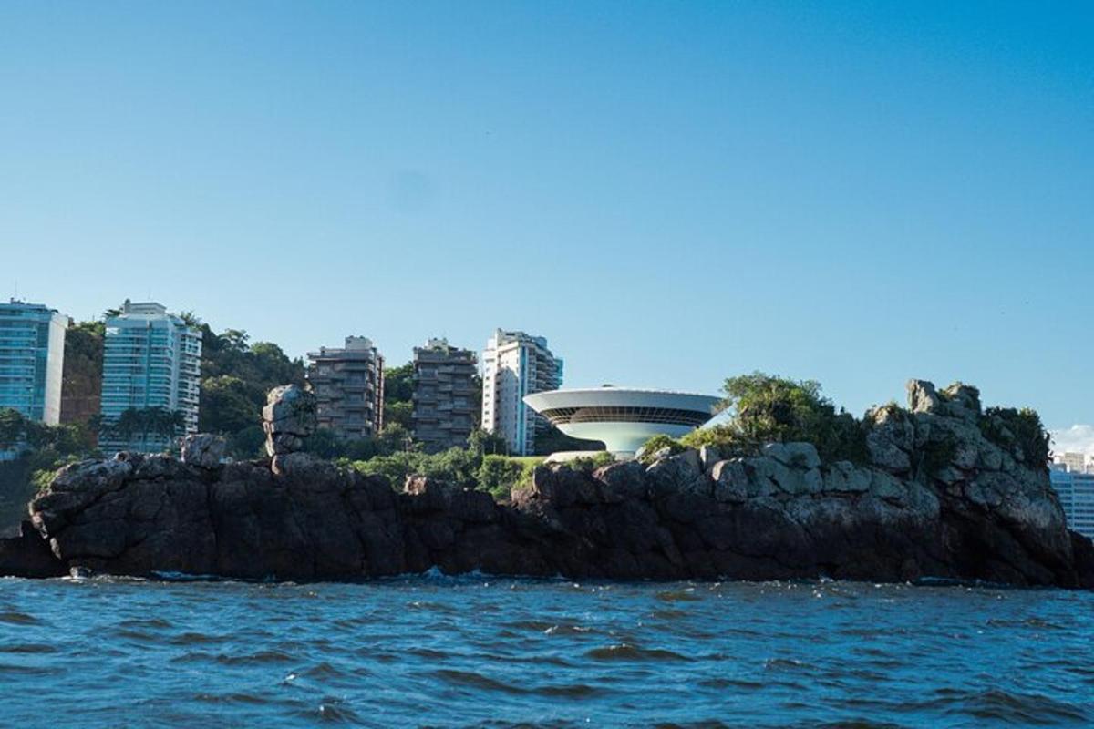 a rock island in the water with buildings in the background