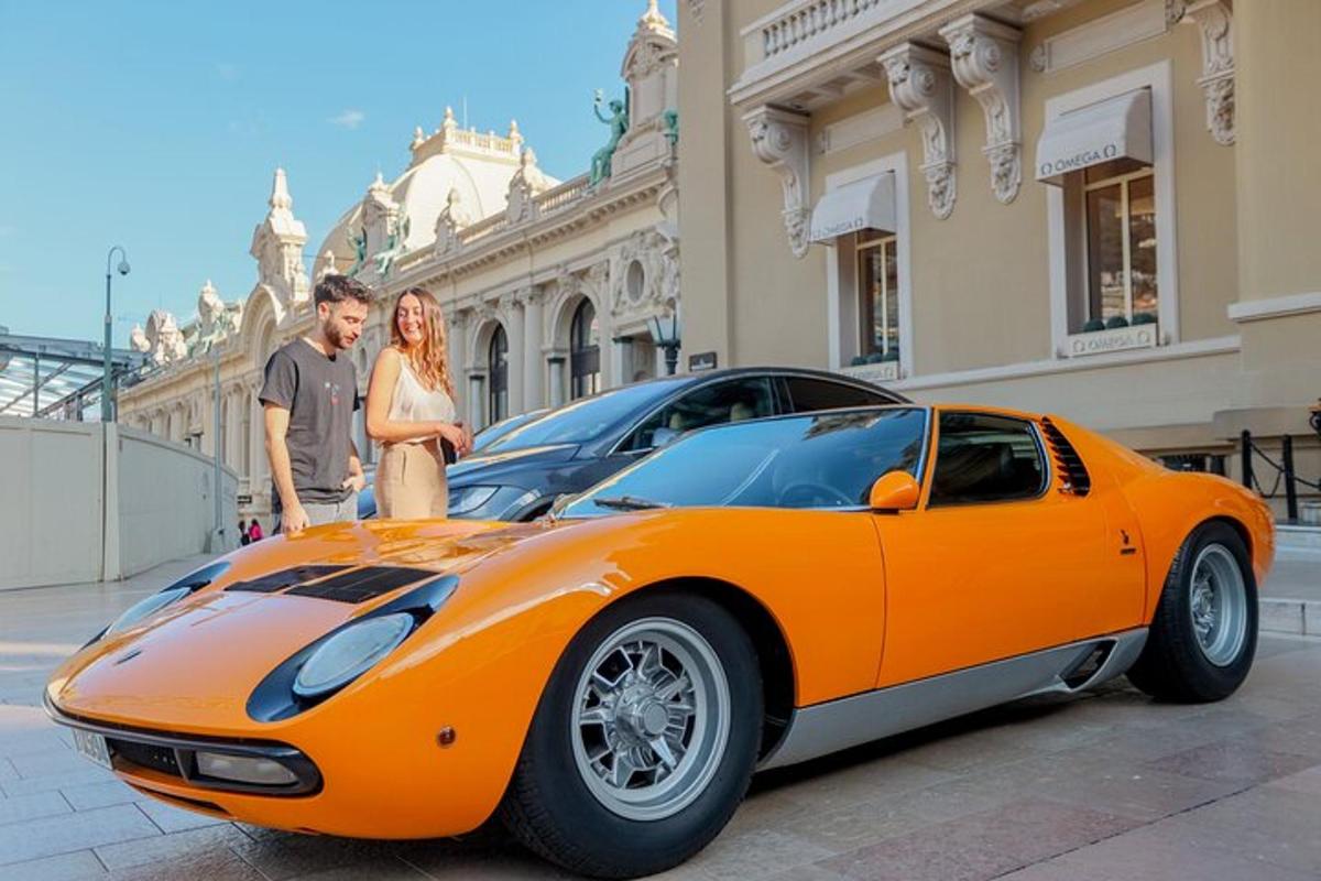 vyras ir moteris stovi šalia oranžinio automobilio