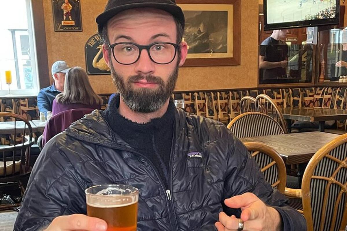 un hombre sentado en una mesa con un vaso de cerveza
