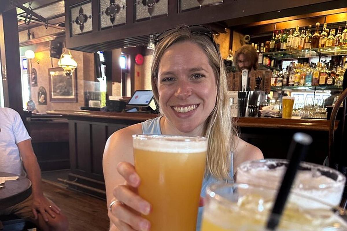Una mujer sentada en un bar sosteniendo un vaso de cerveza