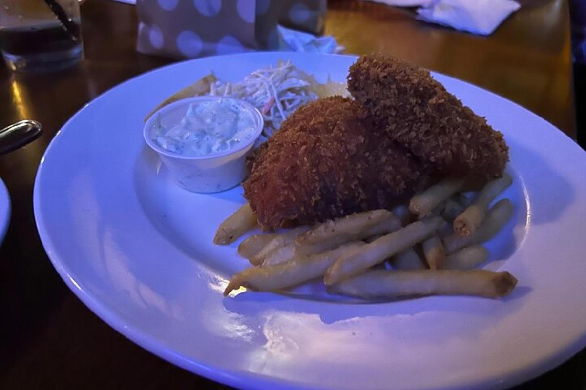Un plato blanco de comida con carne y papas fritas.