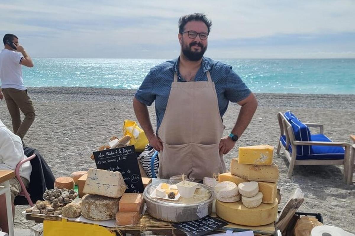 Ένας άντρας που στέκεται δίπλα σε ένα τραπέζι με τυριά στην παραλία