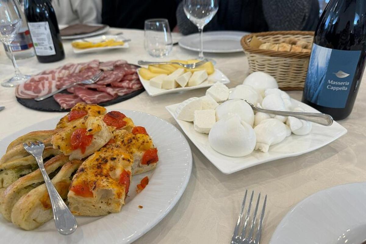 egy asztal tányérokkal megrakott ételekkel és egy üveg borral