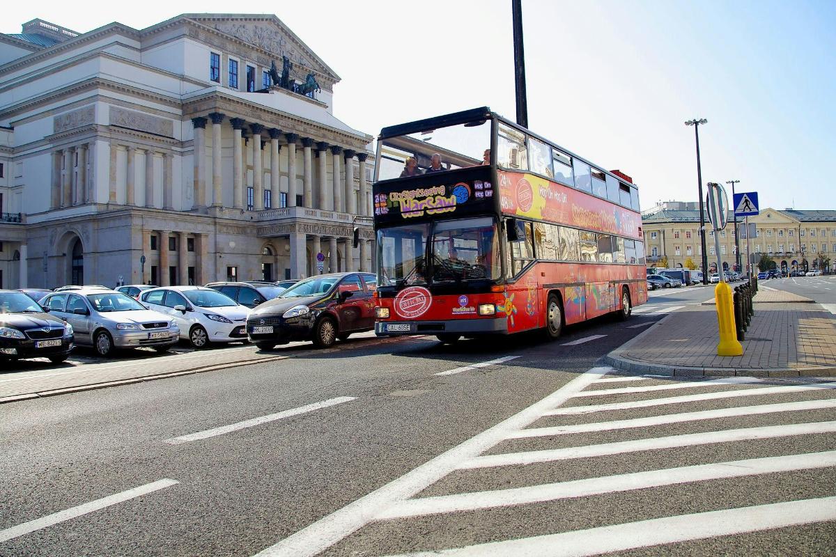 a red double decker bus driving down a city street