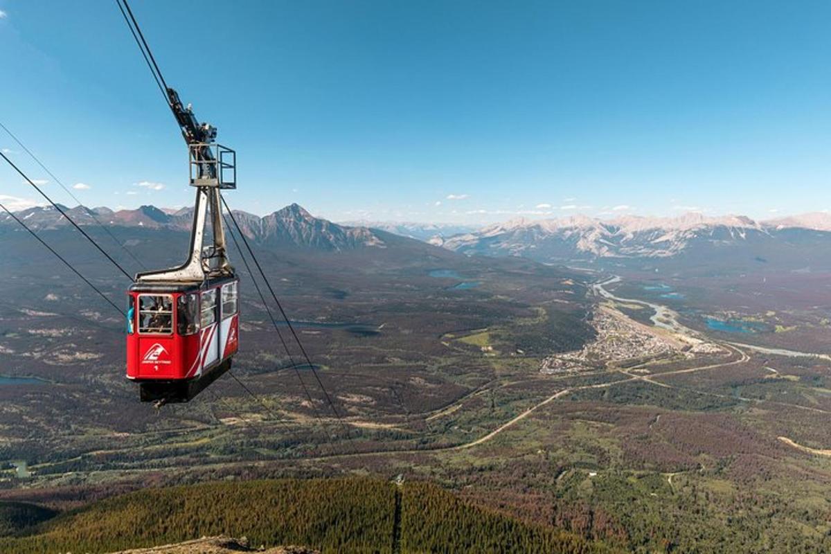 a red cable car flying over a mountain