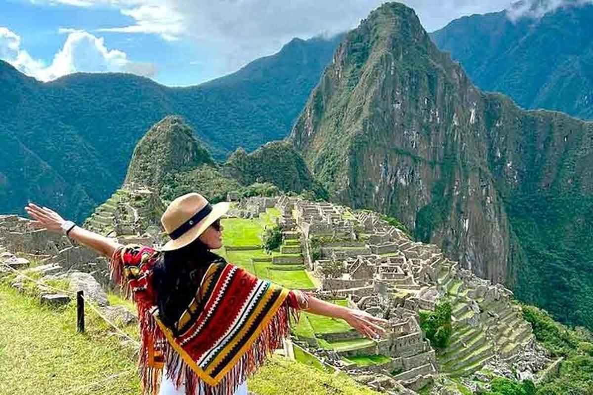 a woman standing on top of a mountain looking at a city