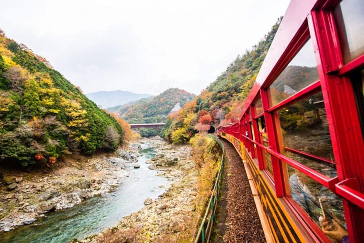 一列红色火车沿着山间的河流行驶