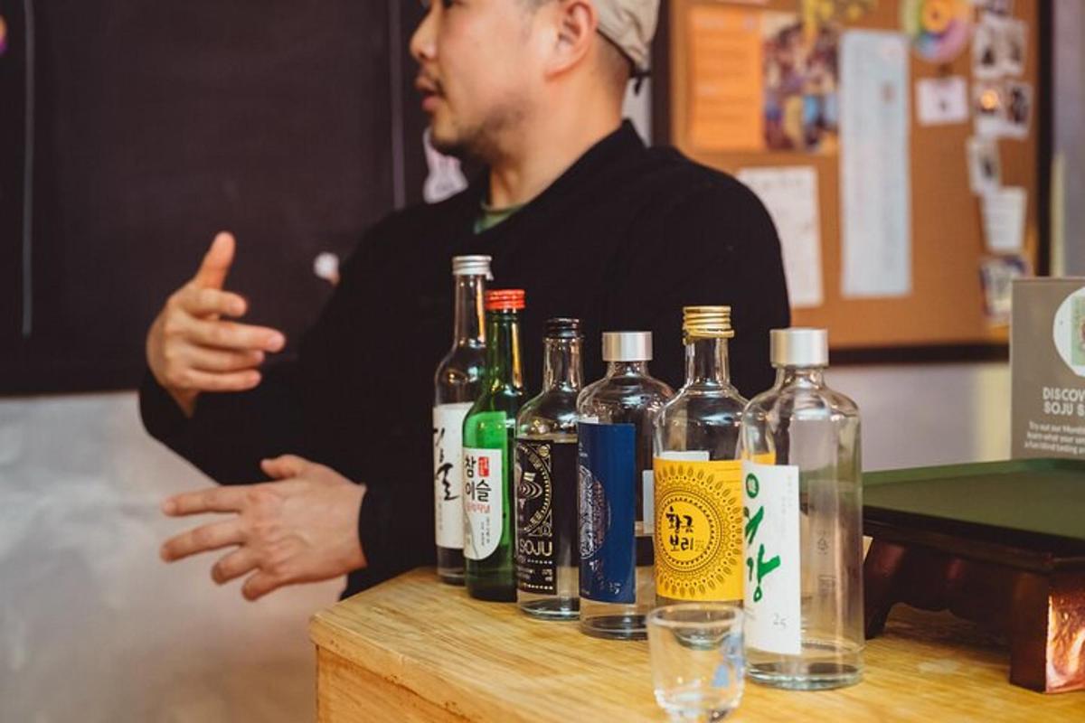 muž ukazuje palec nahoru vedle lahví alkoholu