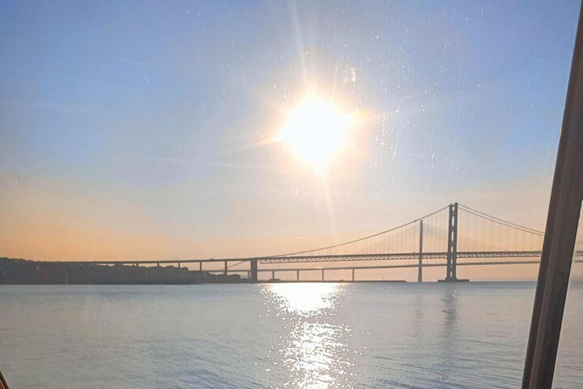 eine Brücke über dem Wasser mit der Sonne am Himmel