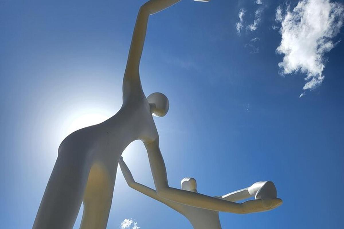 two metal sculptures of a person holding a light