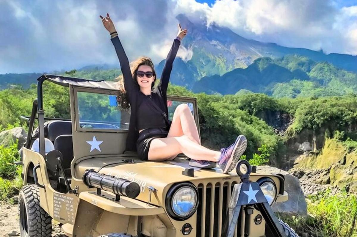 a woman sitting on the bonnet of a jeep