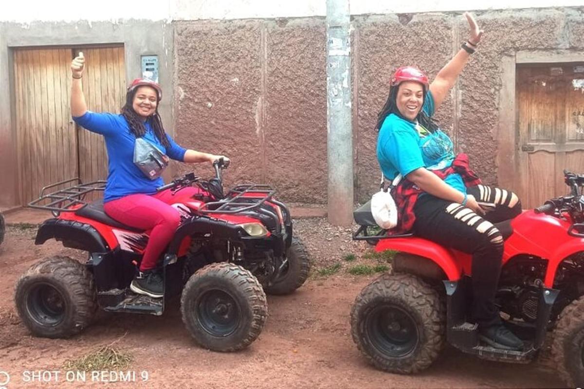 două femei stând pe ATV-uri cu mâinile în aer
