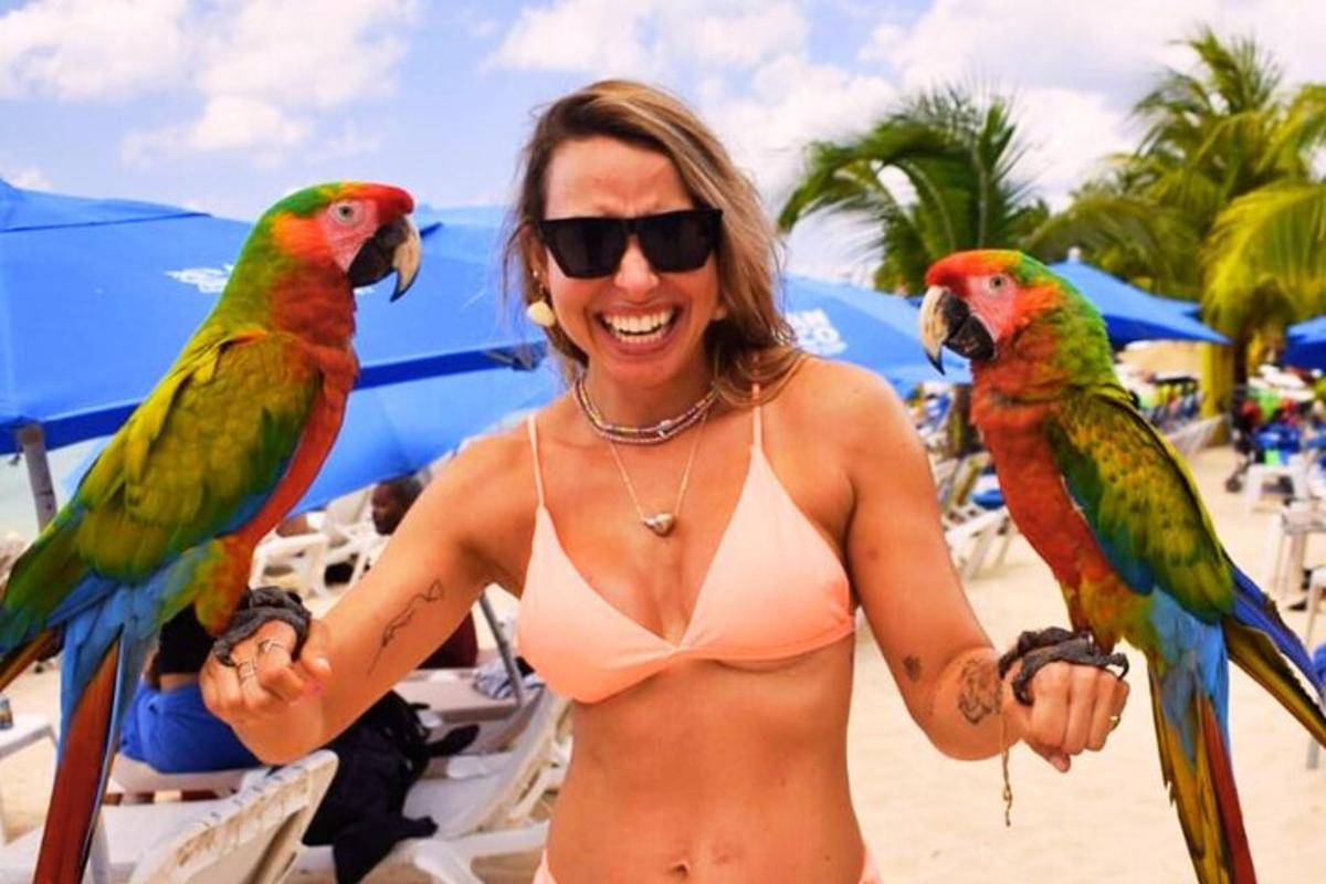 Žena u bikiniju drži dvije ptice na plaži