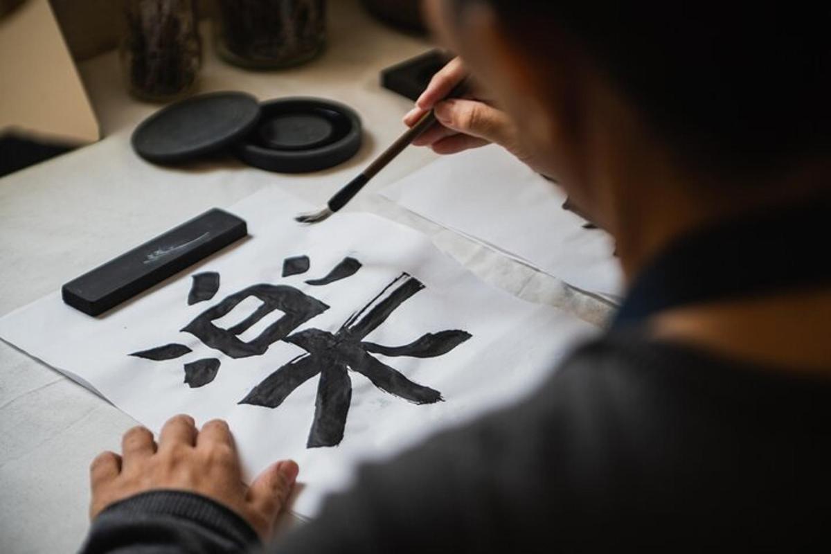 een vrouw die met een penseel op papier schrijft