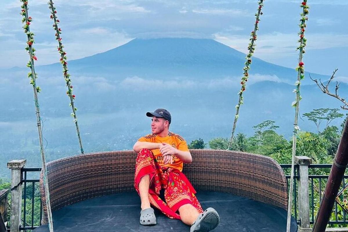 seorang lelaki duduk di atas buaian dengan latar belakang gunung