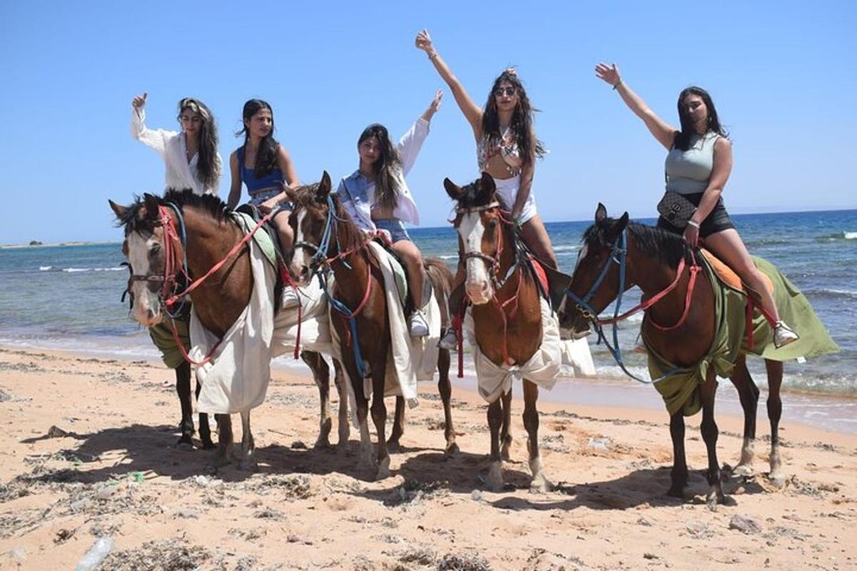 un gruppo di ragazze a cavallo sulla spiaggia